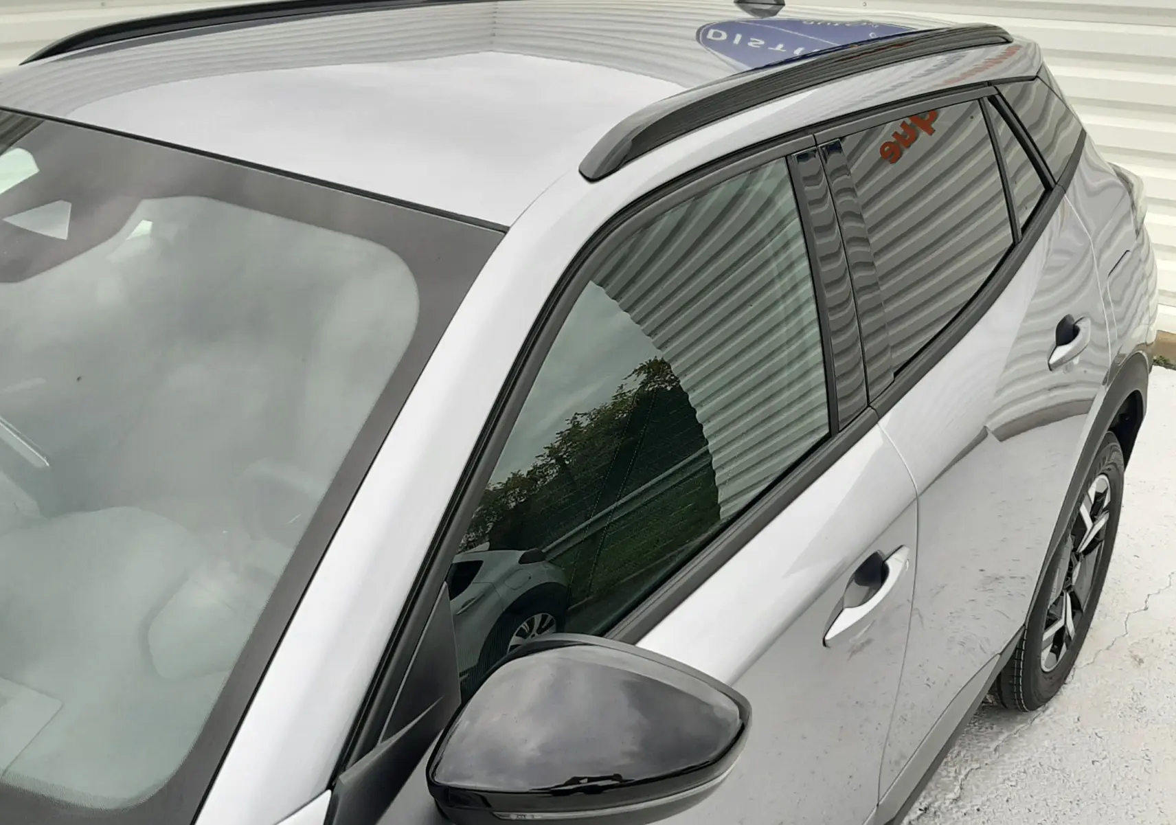 Vue plongeante côté gauche du Peugeot 2008 gris Artense avec toit et rétroviseur noir brillant, jantes alliage visibles.