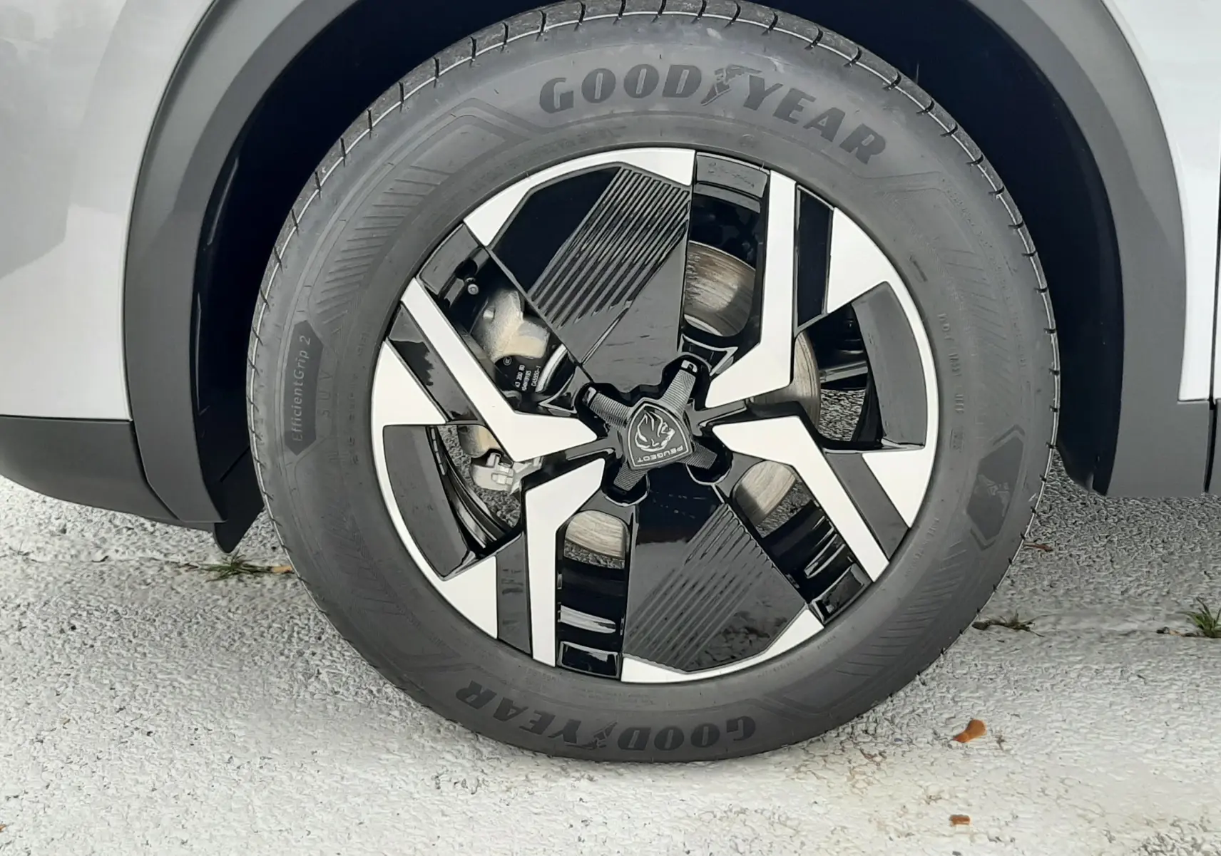 Gros plan sur la roue avant droite d'une Peugeot 2008 gris Artense avec jante noire et argentée au design moderne.