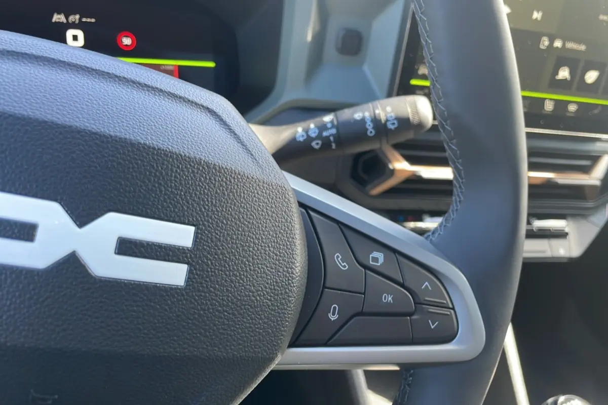 Gros plan sur le volant du Dacia Bigster 2025 avec commandes intégrées et tableau de bord numérique en arrière-plan.