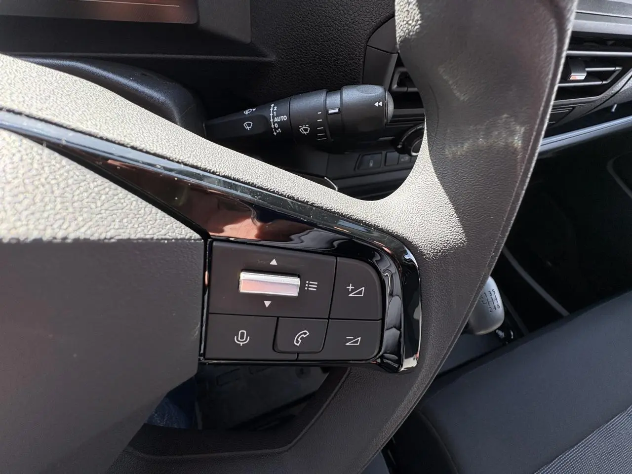 Gros plan sur les commandes au volant et levier de vitesse manuel dans l’habitacle sombre de l’Opel Vivaro blanc.