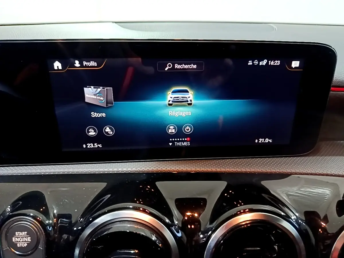 Vue rapprochée de l’écran tactile central et des aérateurs ronds noirs du tableau de bord d’une Mercedes Classe A gris foncé.