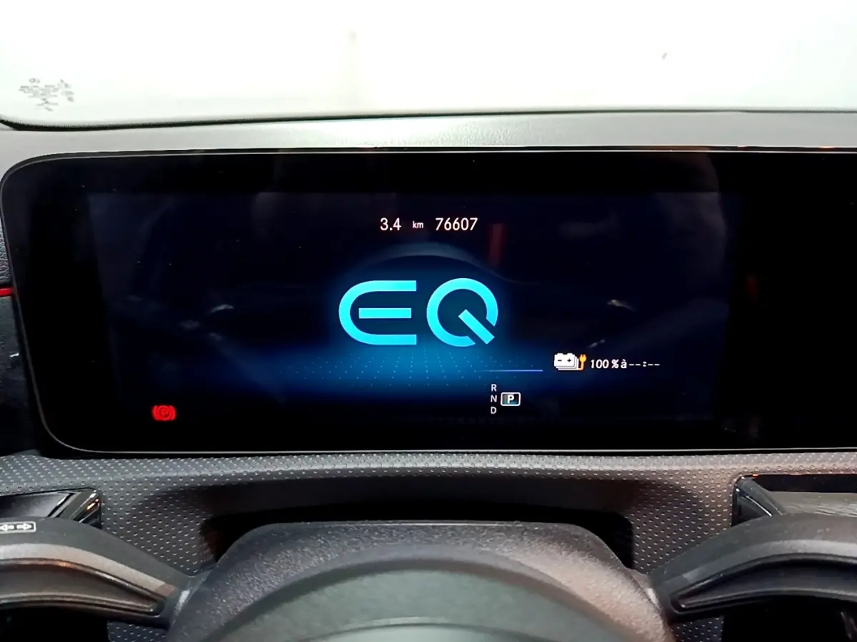 Vue rapprochée de l'écran numérique du tableau de bord de la Mercedes Classe A 250 e AMG Line, affichant le logo EQ bleu.