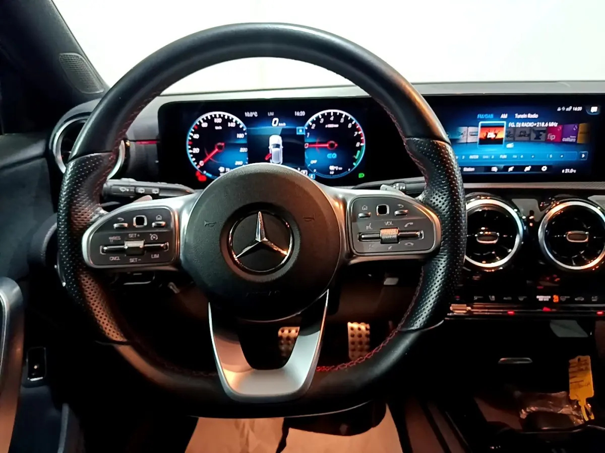 Vue rapprochée du volant cuir et alu d’une Mercedes Classe A 250 e AMG Line 2021 avec tableau de bord numérique.