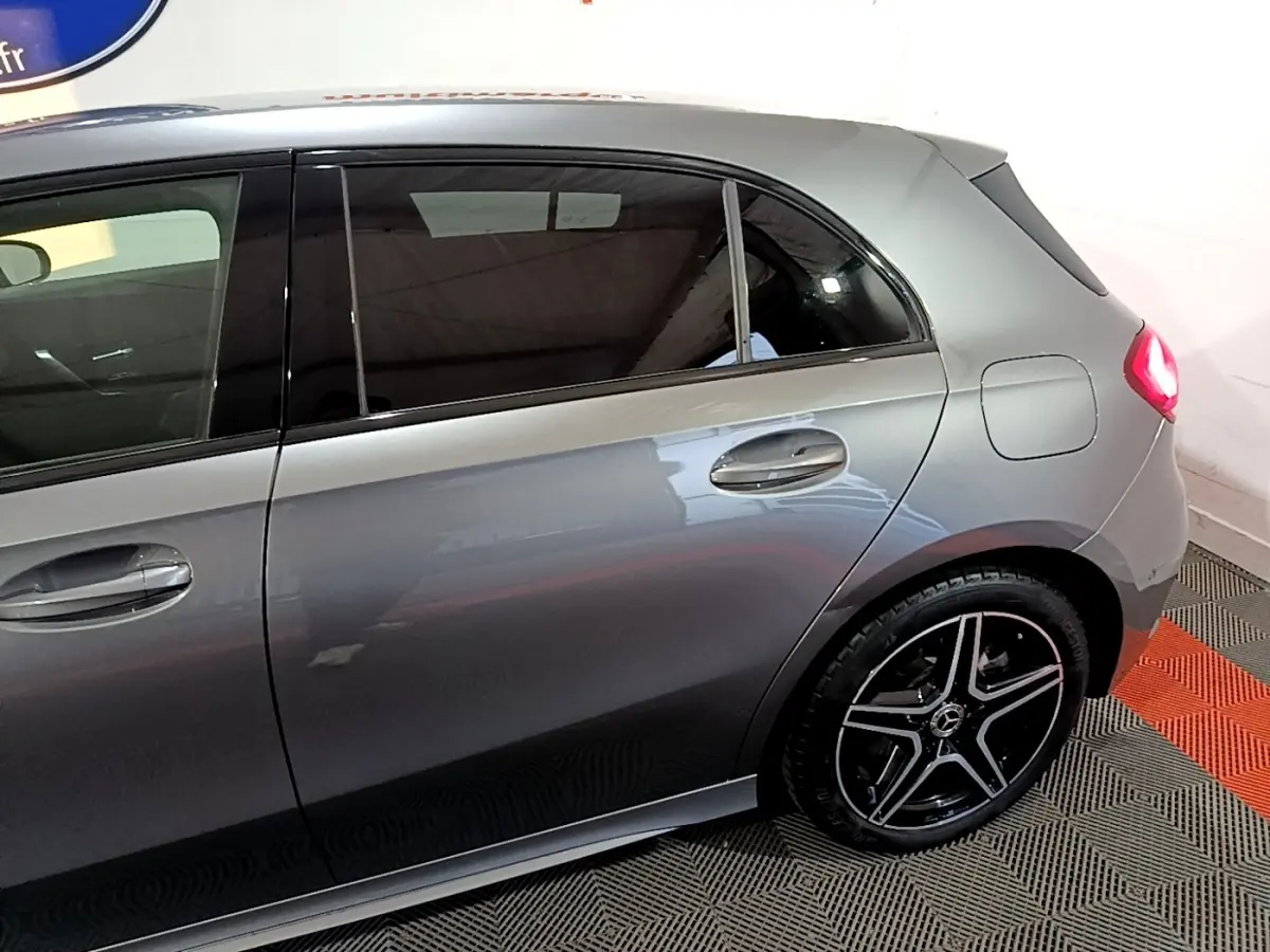 Vue latérale droite d'une Mercedes Classe A 250 e AMG Line gris foncé, avec jantes alliage noires et feux arrière allumés.