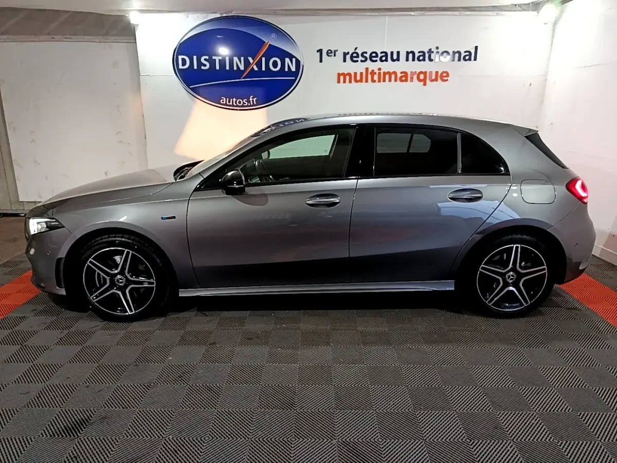 Vue de profil côté gauche d'une Mercedes Classe A 250 e AMG Line gris foncé avec jantes alliage et feux arrière allumés.