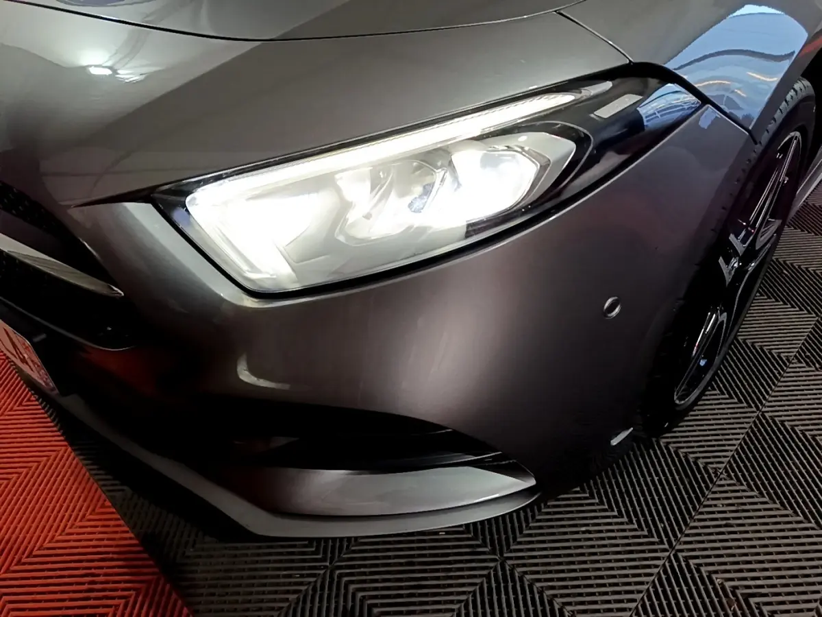 Gros plan sur l'avant droit gris foncé d'une Mercedes Classe A 250 e AMG Line avec phare LED allumé.
