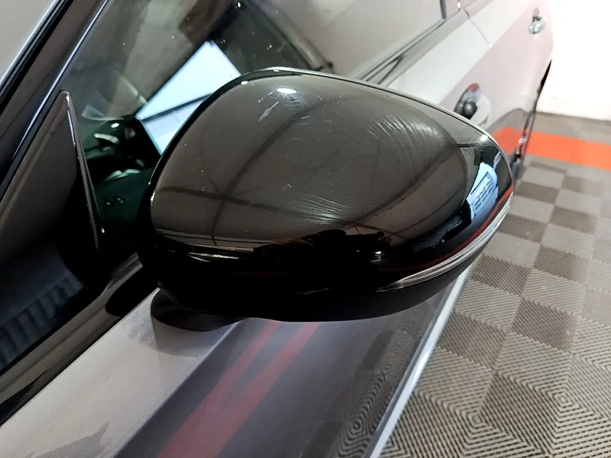 Gros plan sur le rétroviseur côté gauche noir brillant d’une Mercedes Classe A A 250 e AMG Line gris foncé.