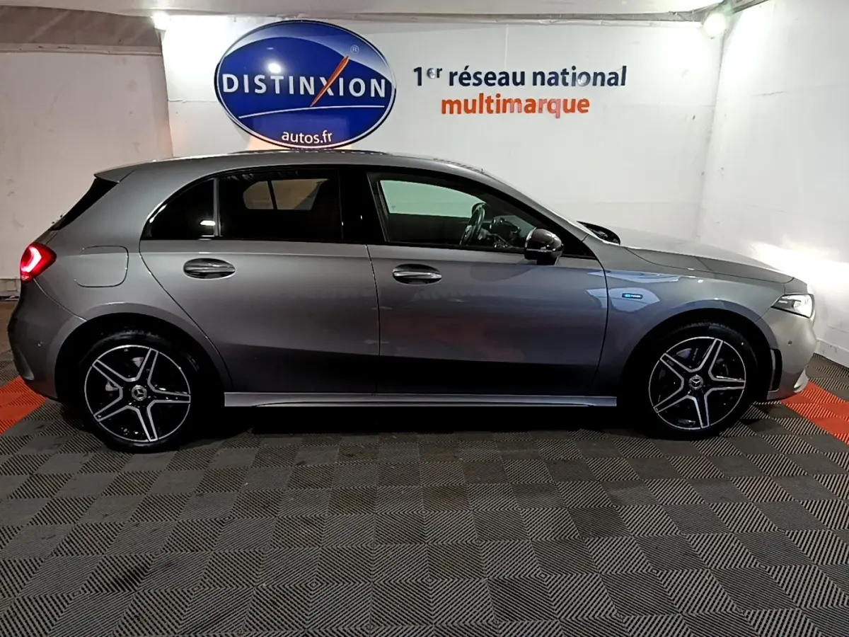 Vue latérale droite d'une Mercedes Classe A 250 e AMG Line gris foncé avec jantes AMG et feux arrière allumés.