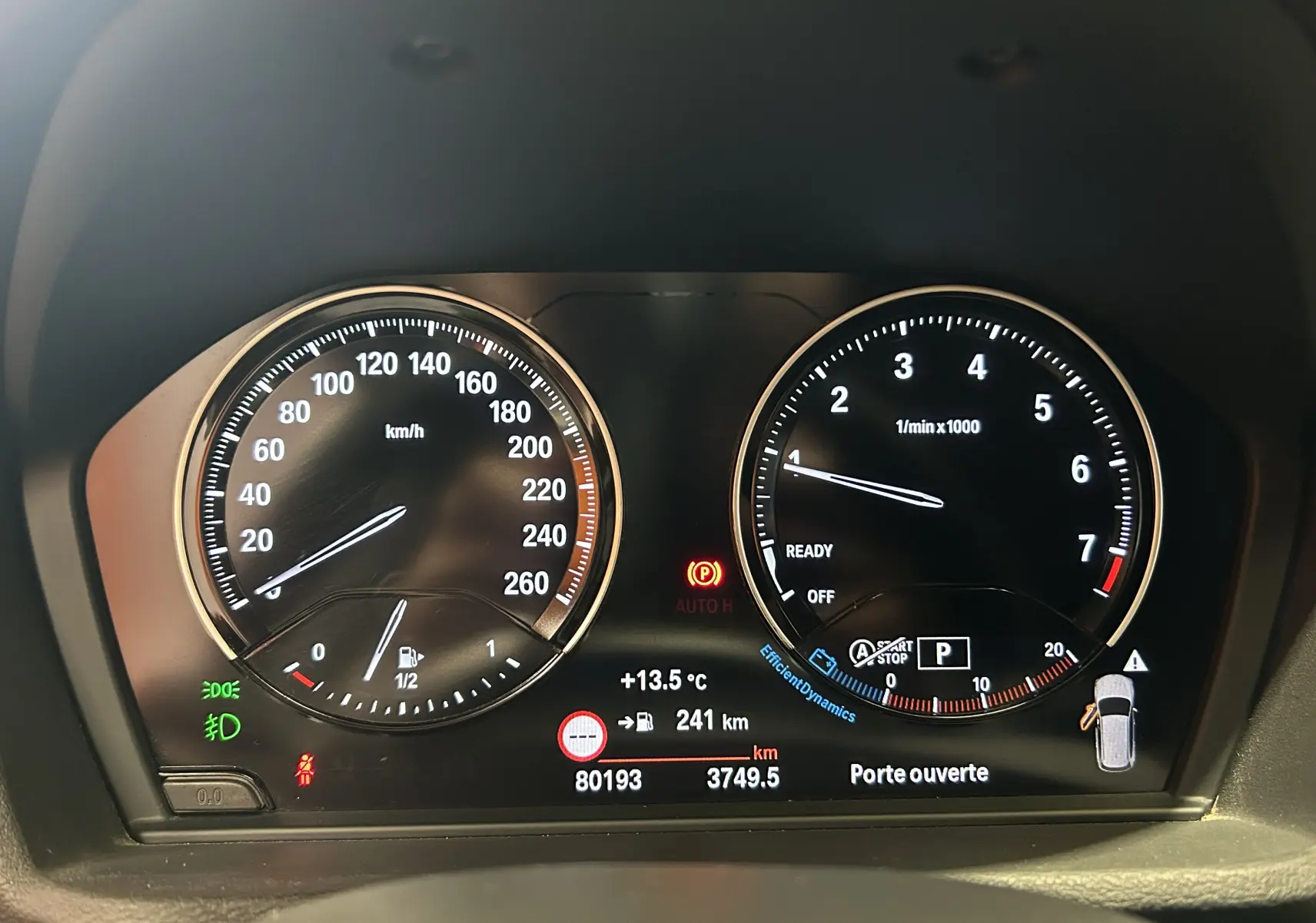 Tableau de bord de BMW X1 blanc 2018, affichage numérique avec compteur vitesse et compte-tours allumés.