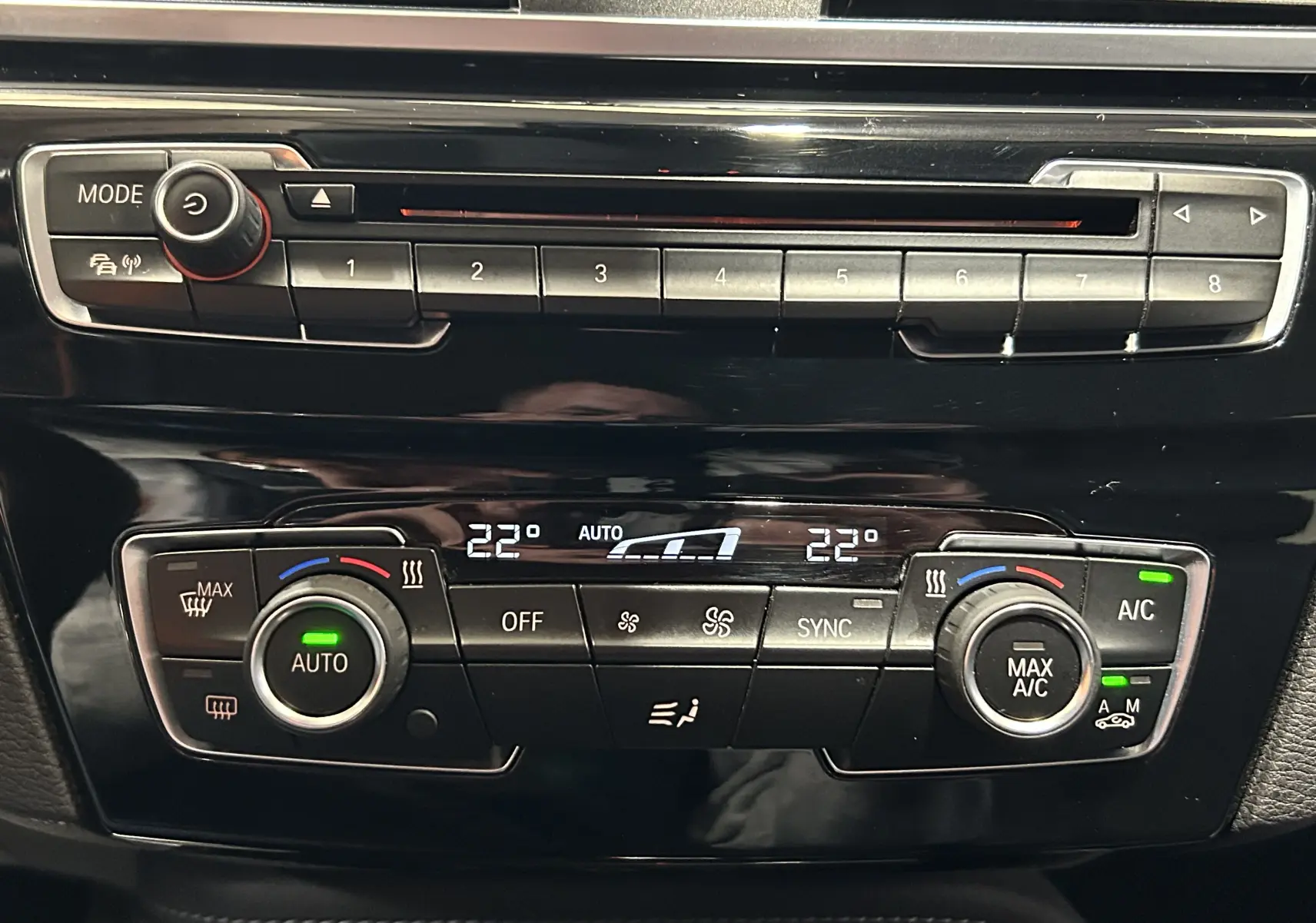 Détail du tableau de bord noir du BMW X1 2018, montrant la climatisation automatique et la radio.