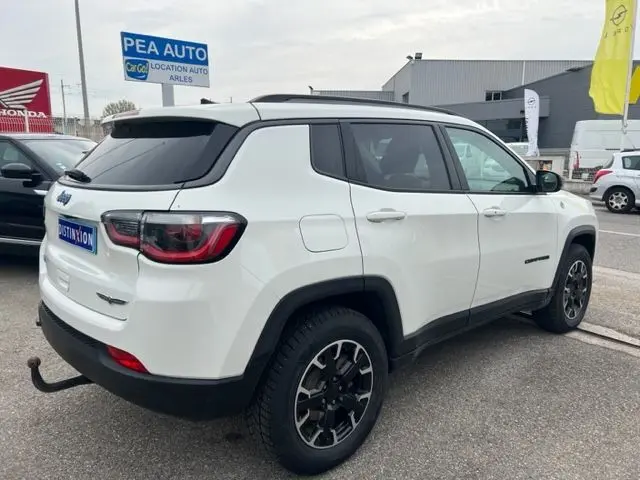 Vue 3/4 arrière droite d'un Jeep Compass blanc hybride rechargeable 2020 avec jantes noires et toit contrasté.