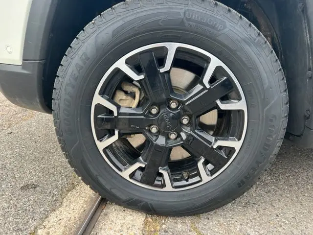 Gros plan sur la roue avant droite du Jeep Compass blanc 2020, jante alliage noir et argent avec pneu Goodyear.