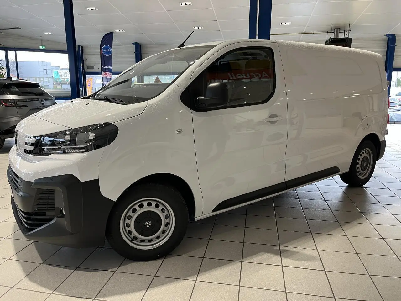Vue de profil côté gauche d'un Peugeot Expert Fourgon blanc 2024 en showroom avec pare-chocs noirs et jantes acier.