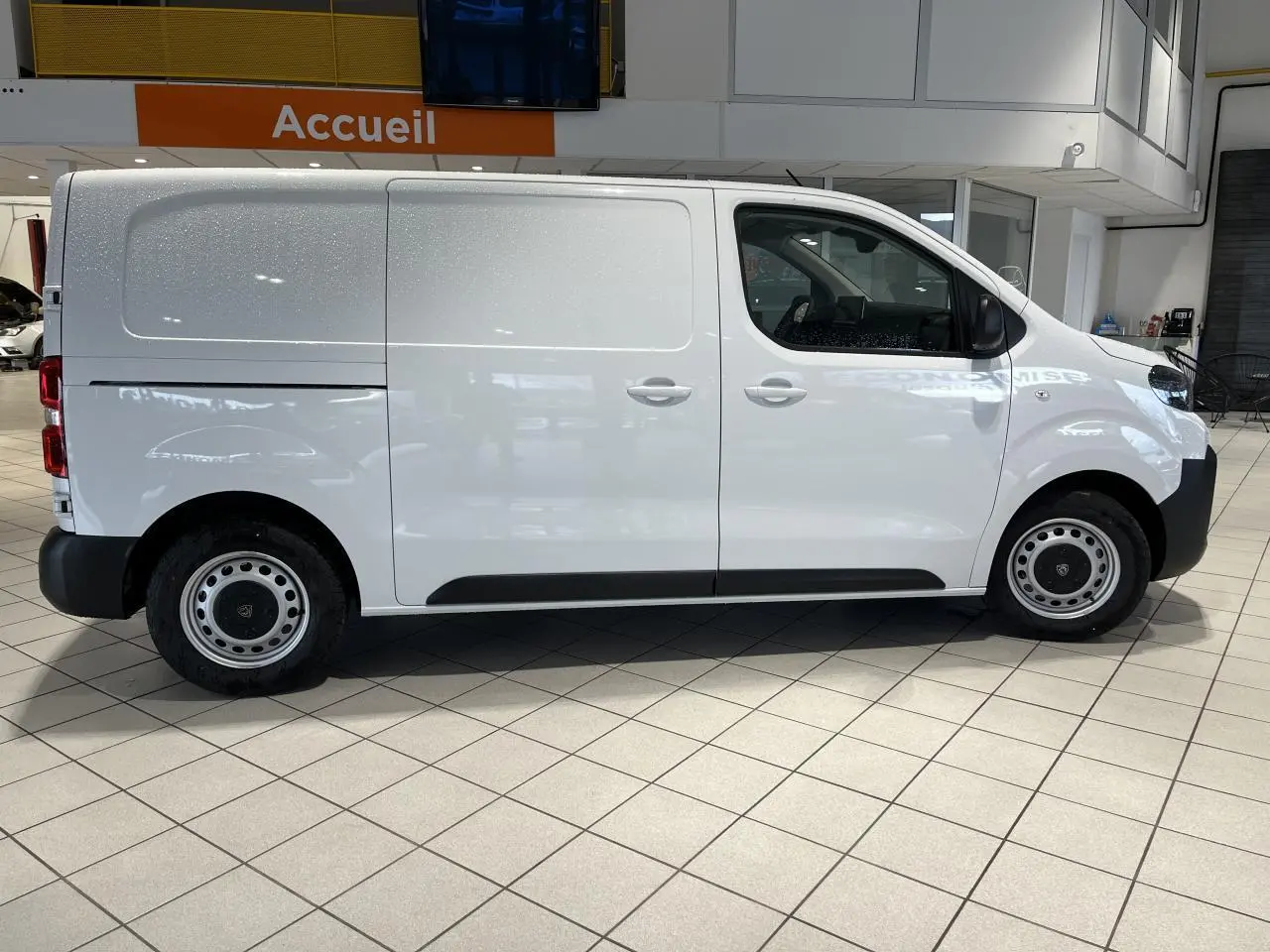 Vue latérale droite d'un Peugeot Expert Fourgon blanc 2024 en showroom, avec jantes acier et poignées de porte assorties.