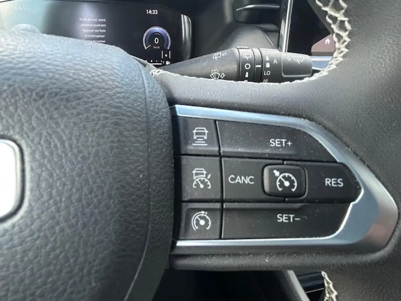 Gros plan sur les commandes du régulateur de vitesse au volant du Jeep Compass 2022, intérieur noir.