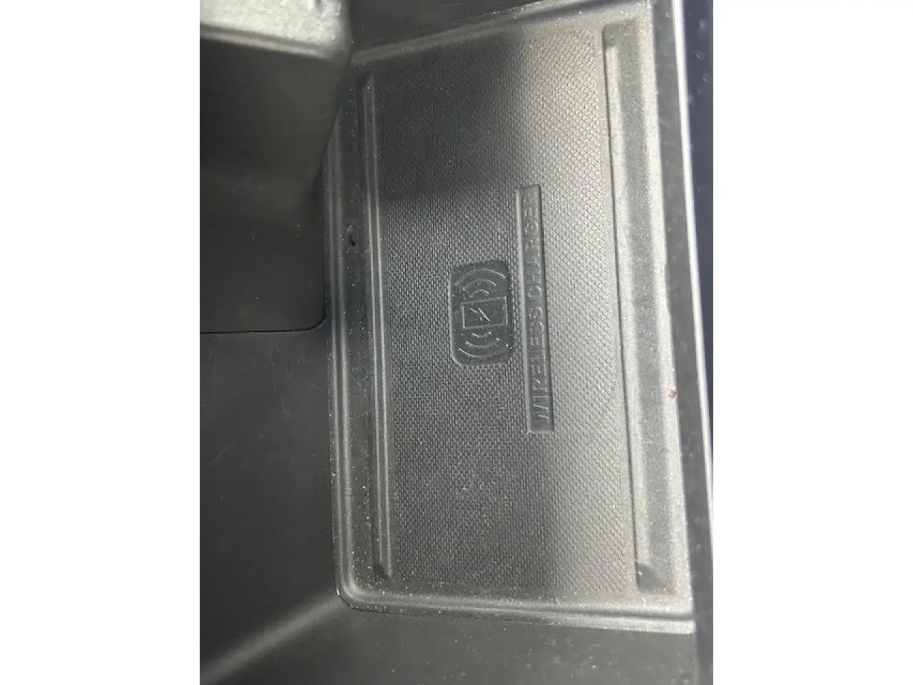 Gros plan sur le chargeur sans fil noir dans l'accoudoir central du Jeep Compass Blue Shade 2022.