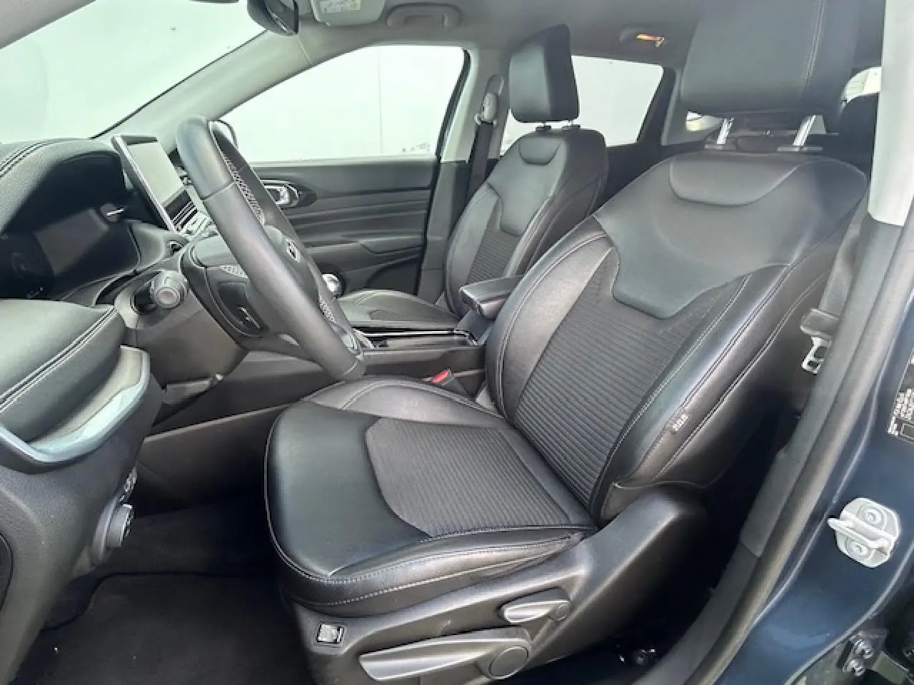 Intérieur avant droit du Jeep Compass 2022 en bleu métallisé, sièges mixte TEP/tissu noirs avec console centrale visible.