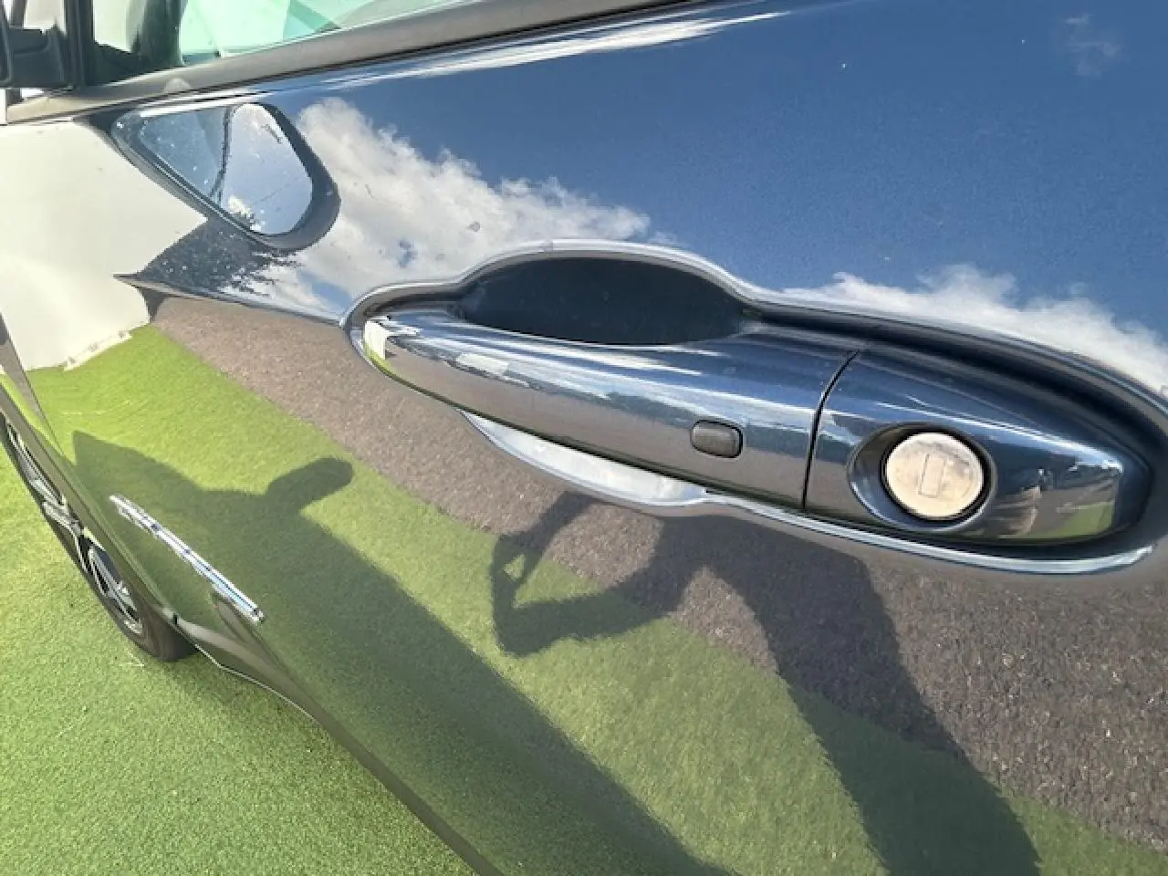 Poignée de porte côté gauche du Jeep Compass 2022 en peinture métallisée Blue Shade reflétant ciel et herbe.