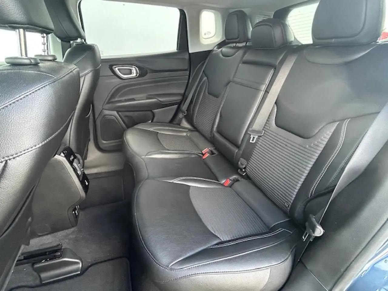 Banquette arrière en cuir noir avec accoudoir central et porte-gobelets, vue côté droit du Jeep Compass 2022 bleu métallisé.