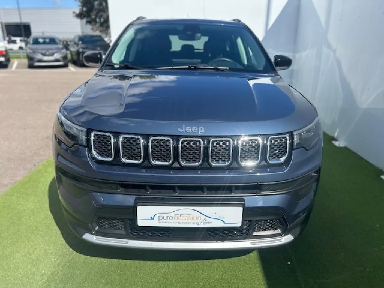Vue frontale d'un Jeep Compass 2022 bleu métallisé avec calandre chromée et logo Jeep visible.
