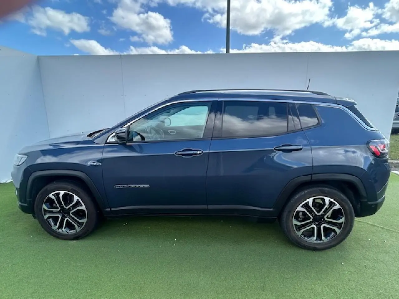 Vue latérale gauche d'un Jeep Compass 2022 bleu métallisé avec jantes alliage 18 pouces et vitres surteintées.