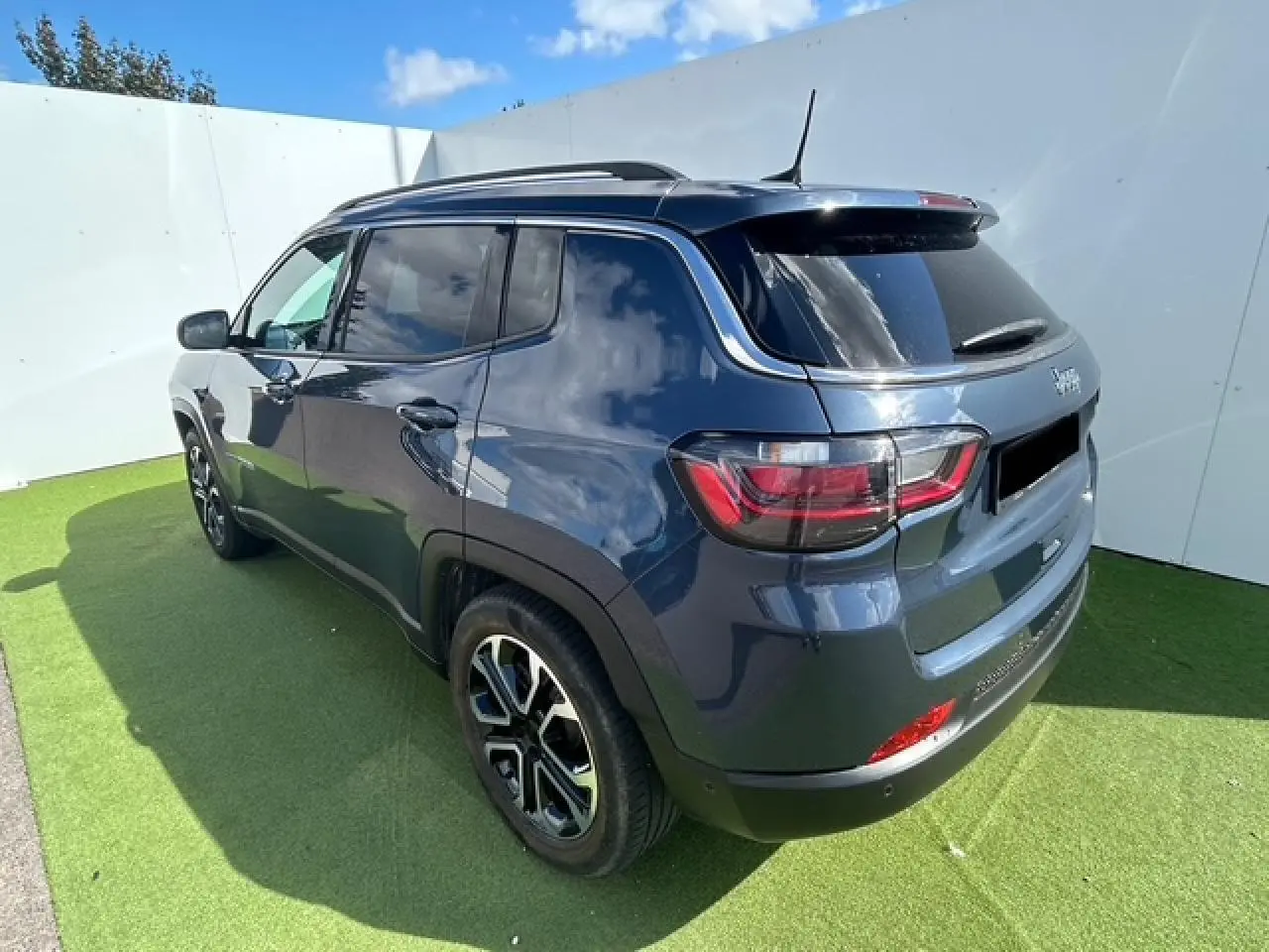 Vue 3/4 arrière droite d'un Jeep Compass bleu métallisé avec jantes alliage 18 pouces et vitres surteintées.