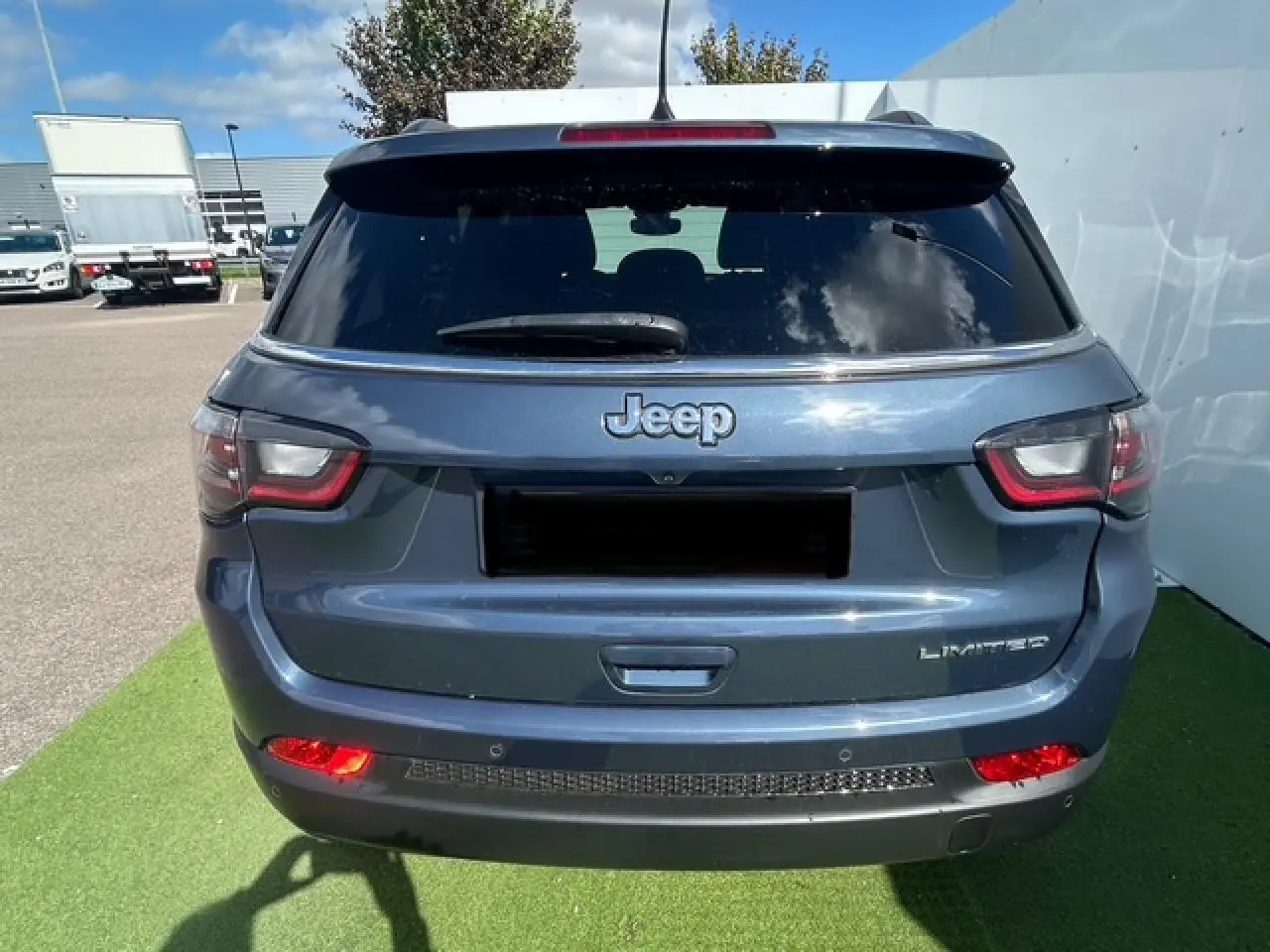 Vue arrière d'un Jeep Compass bleu métallisé avec feux LED et badge Limited visible sur un parking.