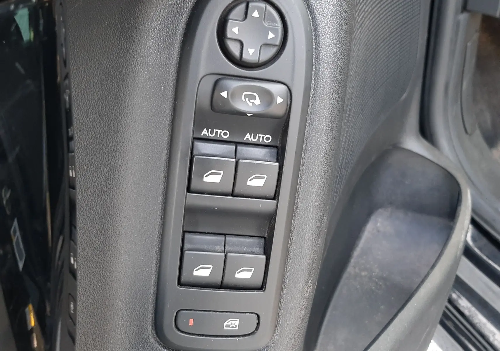 Panneau de commandes des vitres électriques et rétroviseurs sur la porte côté gauche d'une Citroën C3 noire de 2016.