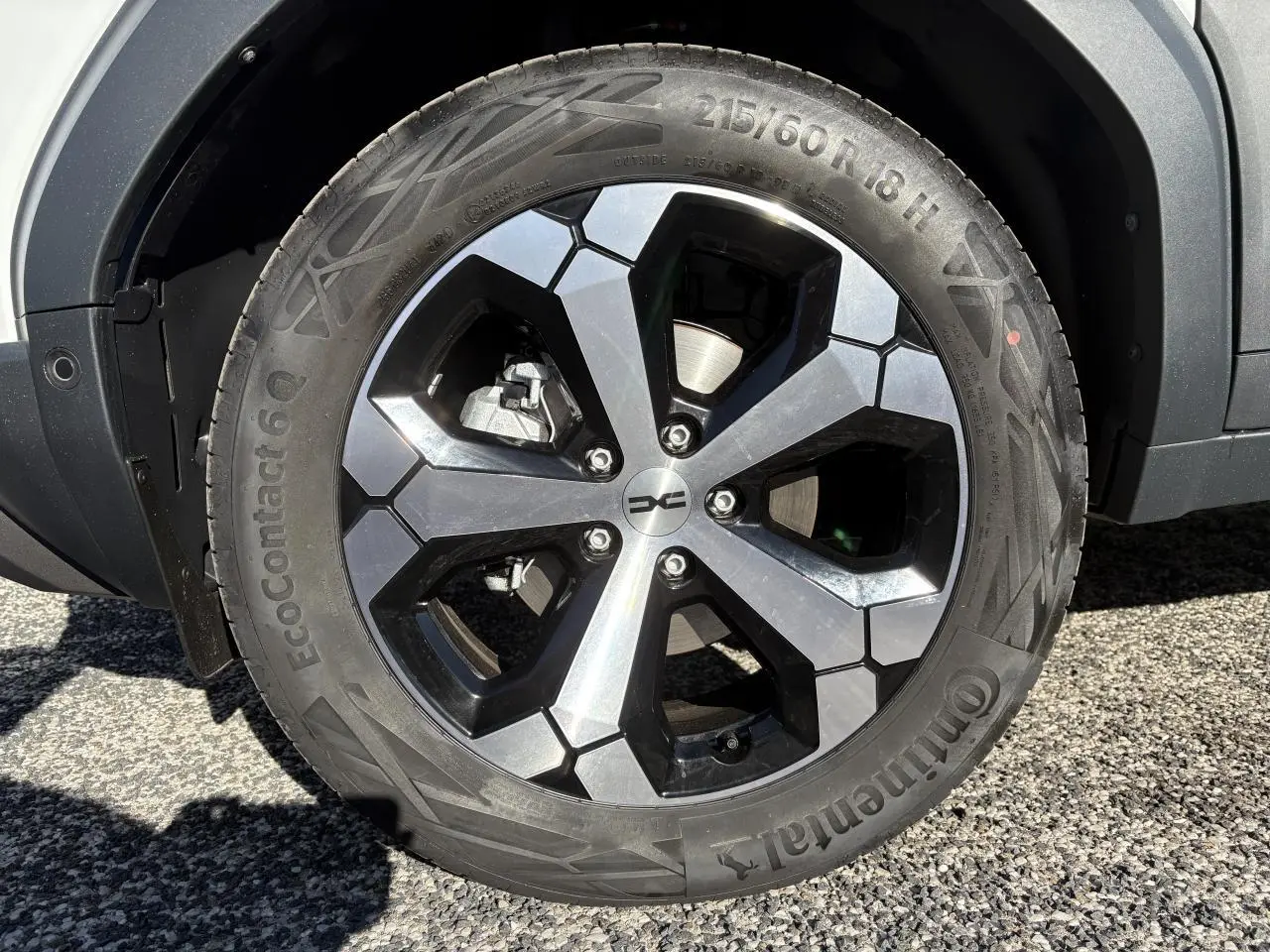 Gros plan sur la roue arrière droite d'un Dacia Duster blanc métallisé 2024 avec passage de roue noir.