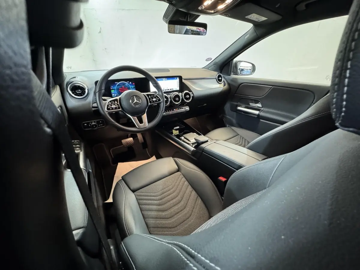 Vue intérieure avant droite du Mercedes GLA 250 e Business Line 2023, volant cuir multifonctions et écran tactile central.
