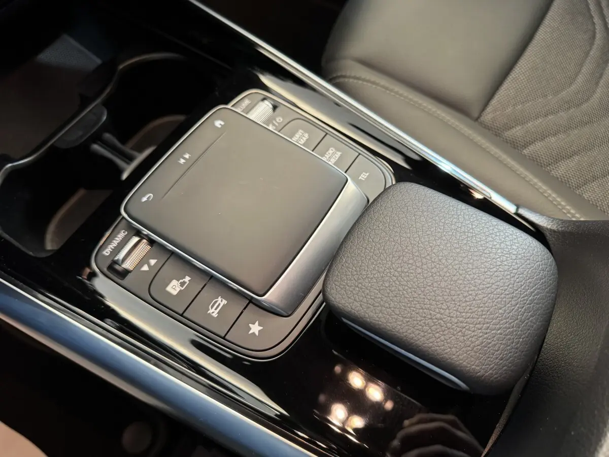 Gros plan sur la console centrale noire avec pavé tactile et accoudoir cuir gris du Mercedes GLA 250 e Business Line 2023.