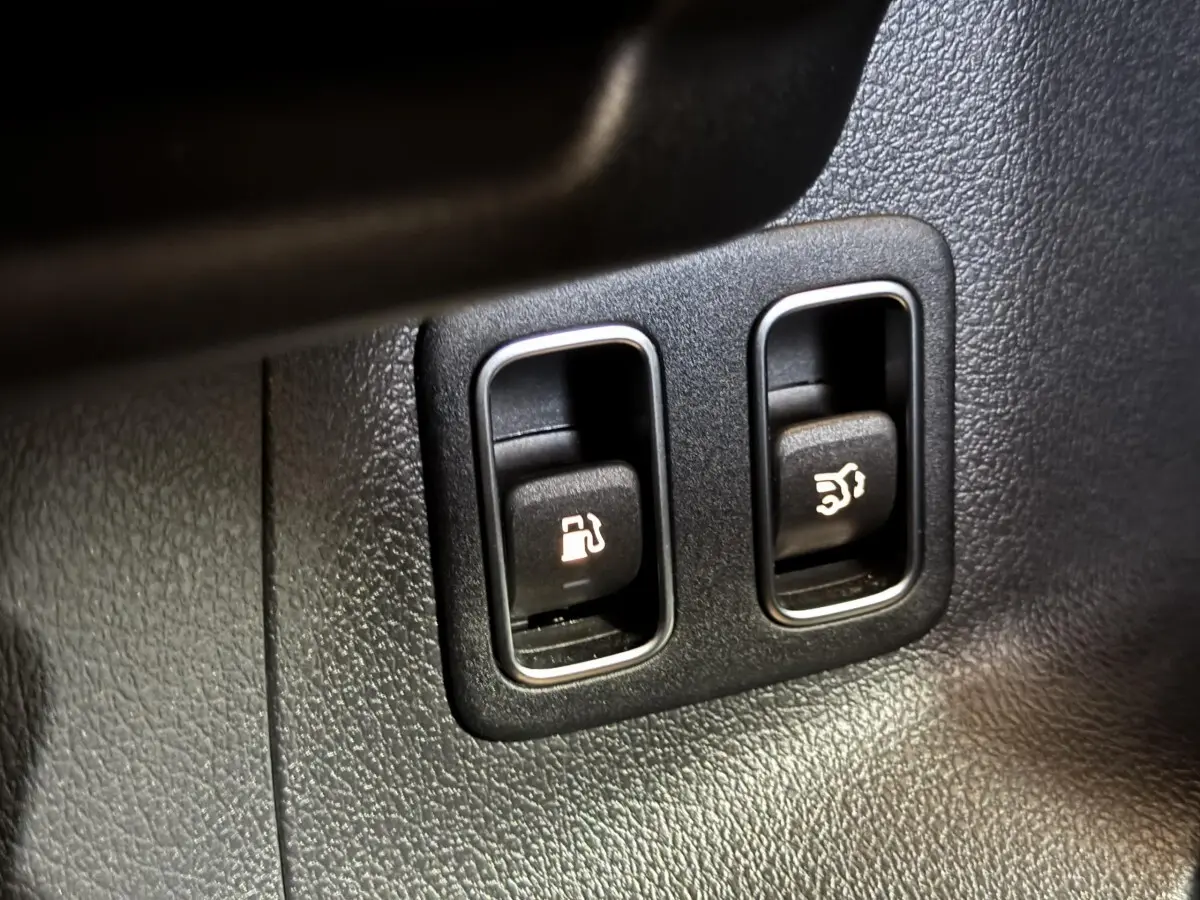 Gros plan sur les boutons d’ouverture du réservoir et du coffre dans l’habitacle du Mercedes GLA 250 e gris foncé.