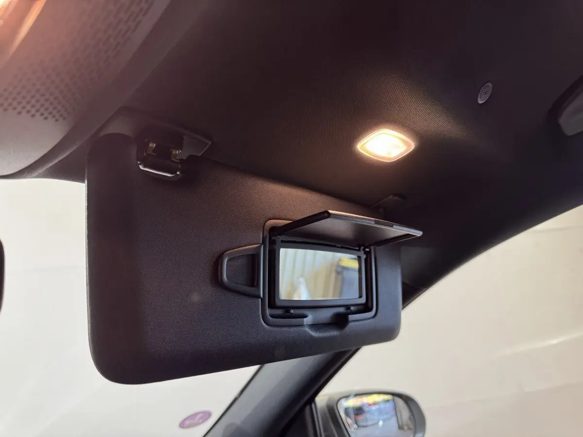 Détail du pare-soleil côté conducteur avec miroir éclairé dans l’habitacle sombre d’une Mercedes GLA 250 e gris foncé.
