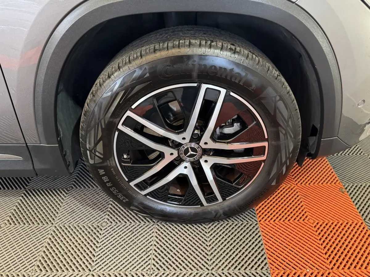 Gros plan sur la roue avant droite avec jante alliage noire et argentée du Mercedes GLA 250 e gris foncé.