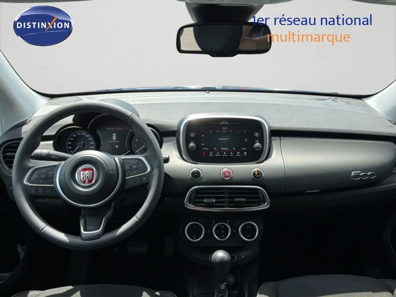Vue intérieure du tableau de bord de la Fiat 500X 2024, avec volant multifonction et écran tactile central.