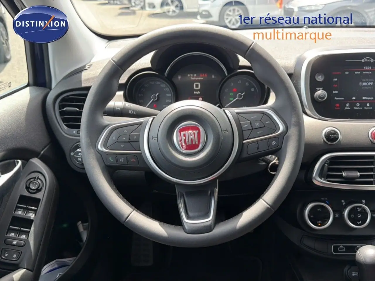 Vue intérieure centrée sur le volant du Fiat 500X 2024, avec tableau de bord et écran tactile visibles.