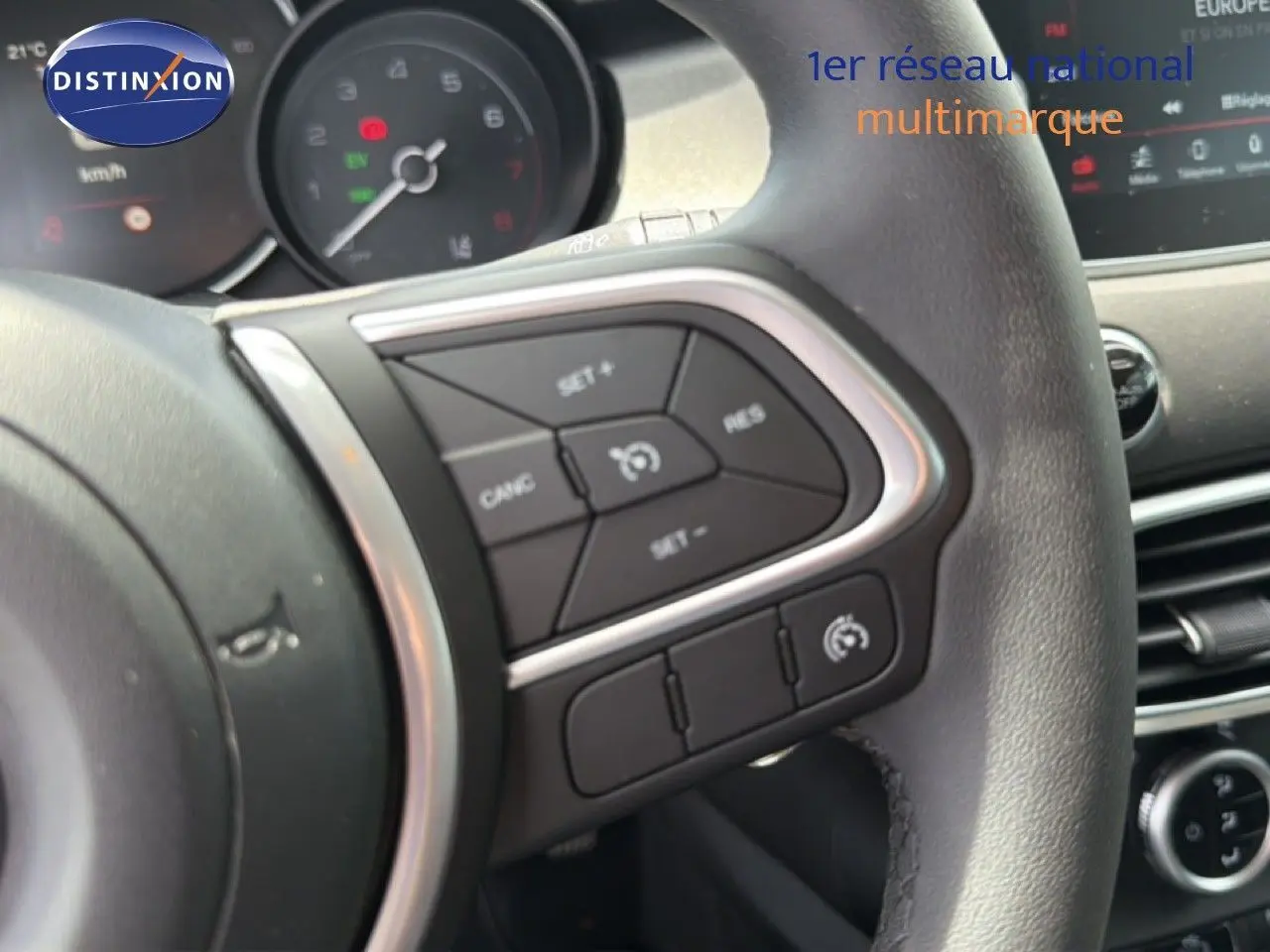 Gros plan sur le volant côté gauche du Fiat 500X 2024 avec commandes de régulateur de vitesse et tableau de bord partiel.