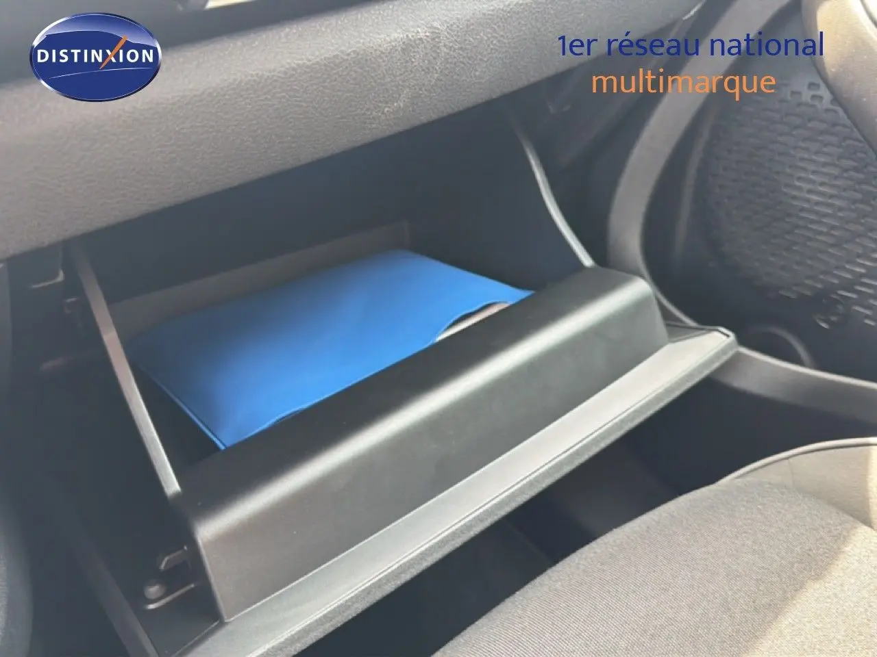 Gant de boîte à gants ouvert avec un manuel bleu à l'intérieur dans une Fiat 500X 2024, vue intérieure côté passager.