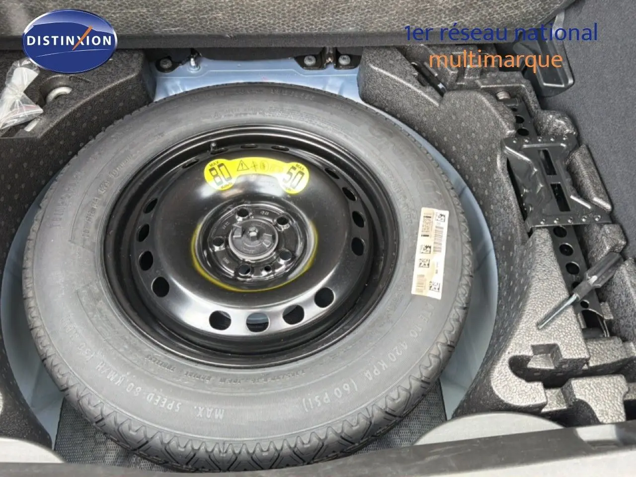 Vue rapprochée de la roue de secours noire dans le coffre d'une FIAT 500X Bleu Venezia 2024.