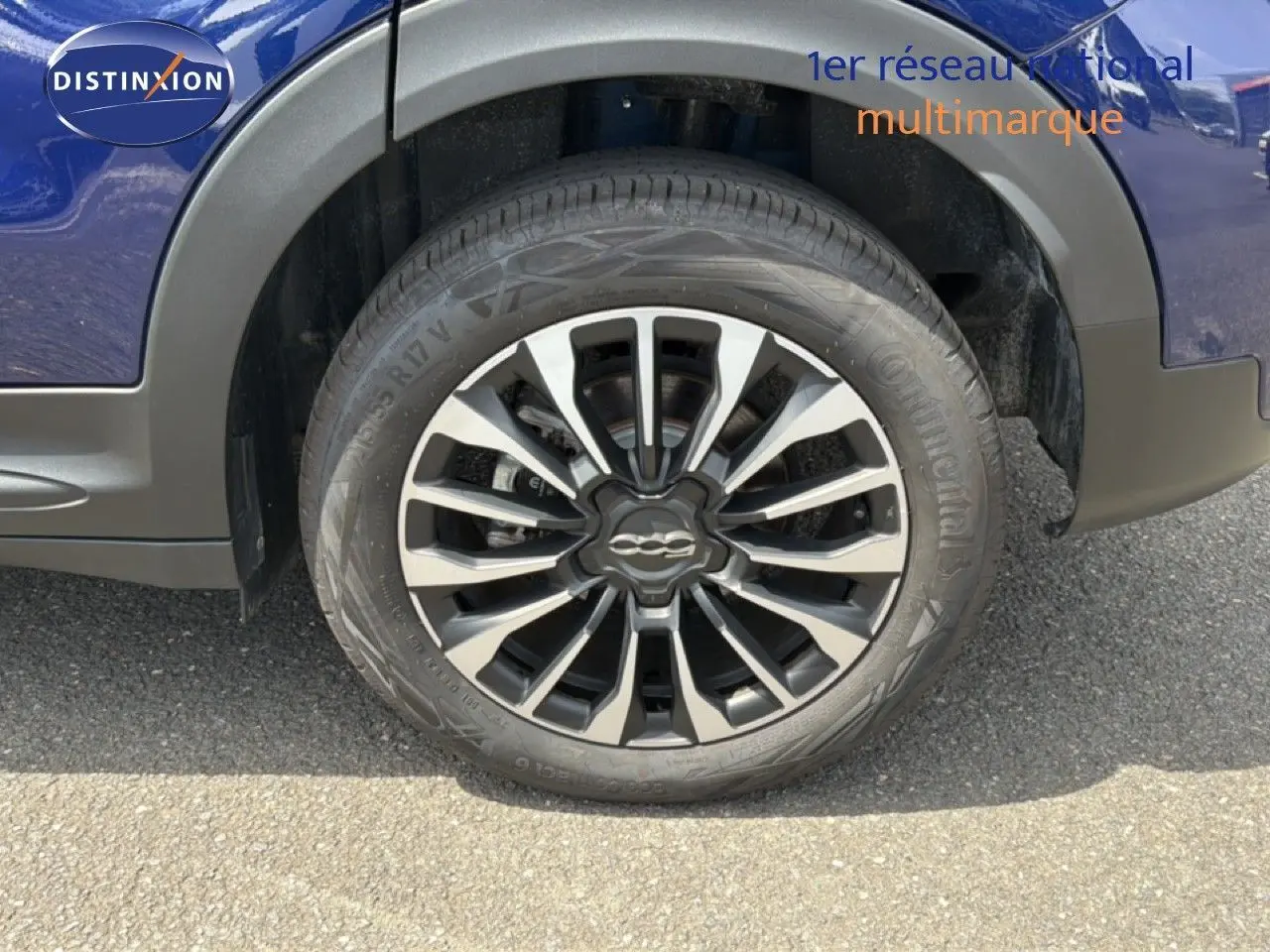Gros plan sur la roue avant droite d'une FIAT 500X bleu Venezia avec jante alliage bicolore et logo central.