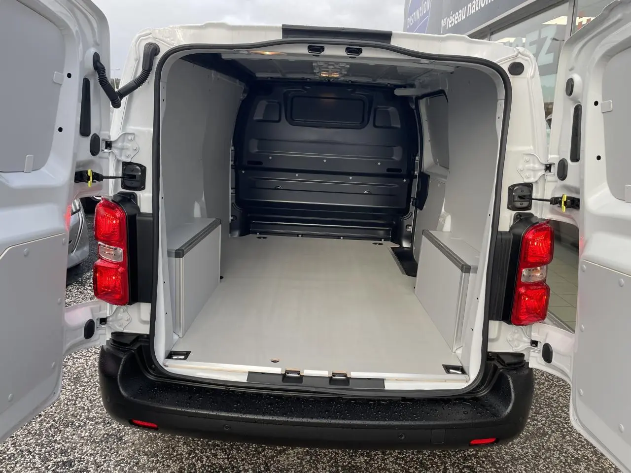 Vue arrière ouverte d’un Opel Vivaro blanc 2024 avec intérieur de chargement équipé de plancher et coffrages en bois.