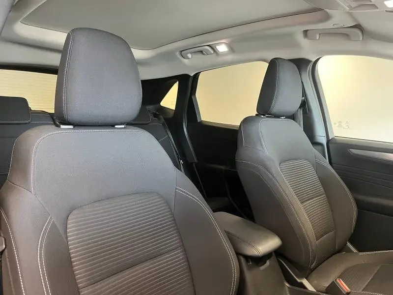 Vue intérieure avant du Ford Kuga 2022 avec sièges sport noirs et toit panoramique éclairé