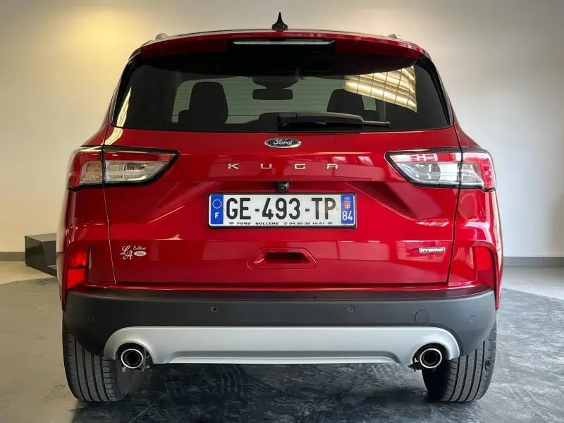 Vue arrière du Ford Kuga 2022 en rouge Premium Lucid avec double sortie d’échappement et toit panoramique visible.