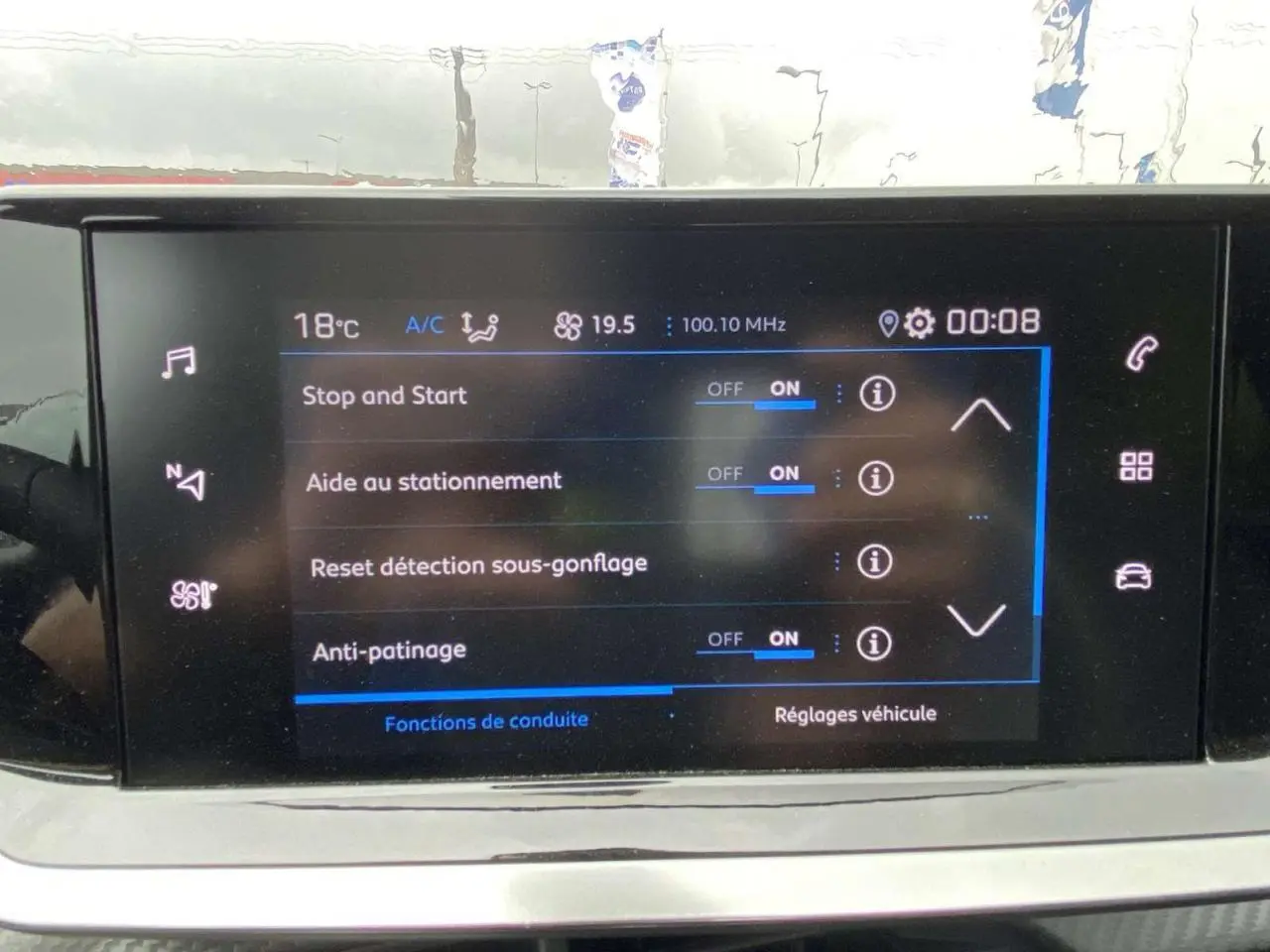Écran tactile central de la Peugeot 208 noir métallisé affichant les réglages d’aide au stationnement et conduite.