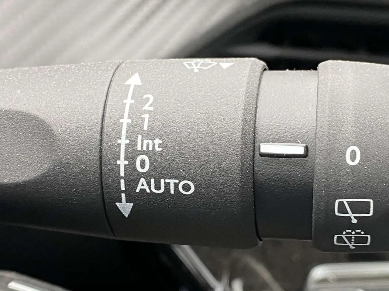 Gros plan sur la commande d’essuie-glace automatique du Peugeot 208 noir métallisé, version 2023 Allure.