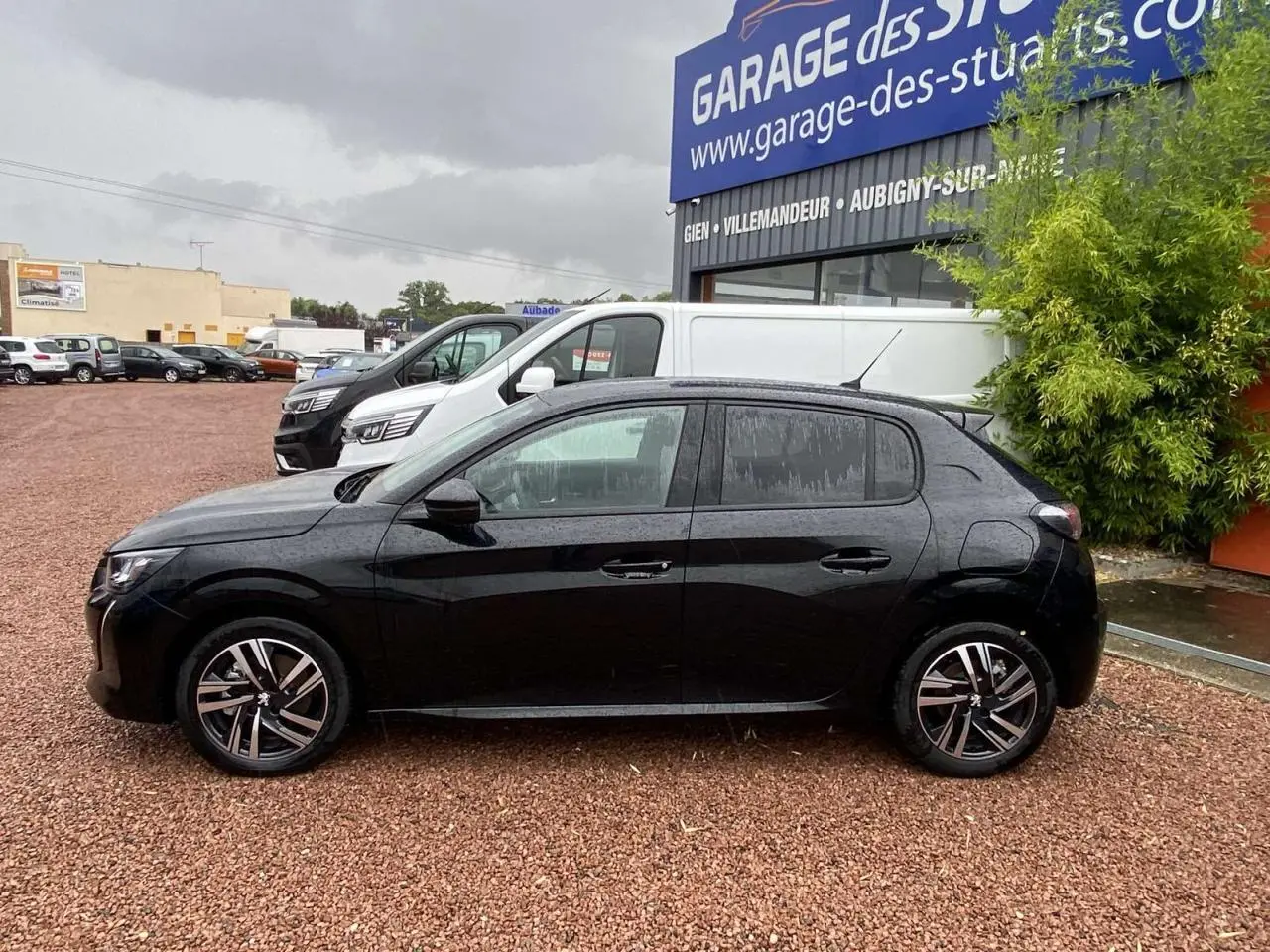 Profil côté gauche de la Peugeot 208 noire métallisée 2023 avec jantes alliage diamantées et vitres teintées.