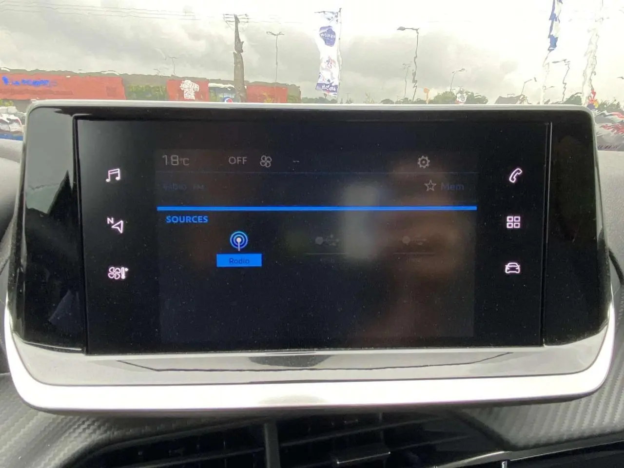 Écran tactile central de la Peugeot 208 2023 affichant les sources audio avec interface moderne et icônes lumineuses.