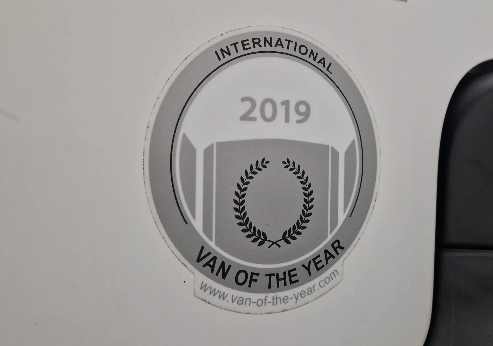 Gros plan sur l'autocollant "International Van of the Year 2019" apposé sur la porte blanche d'un Citroën Berlingo.