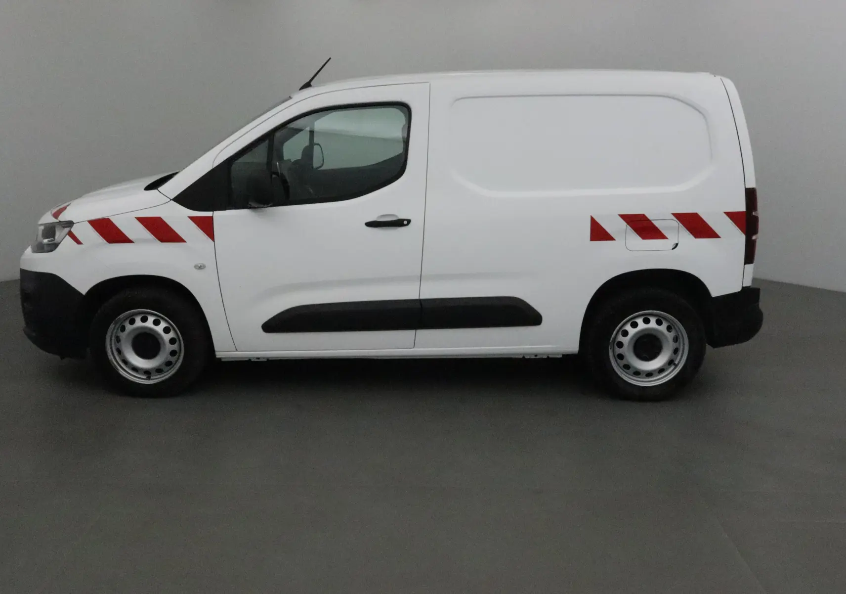 Vue de profil côté gauche d'un utilitaire Citroën Berlingo blanc avec bandes rouges diagonales sur la carrosserie.