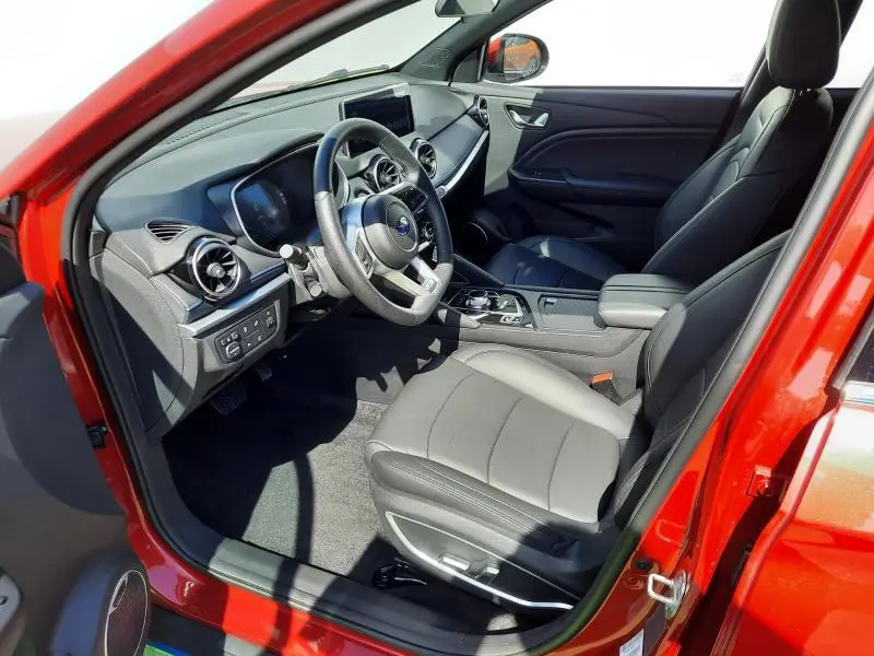 Intérieur avant droit du SERES 3 rouge carmin 2023, sièges en similicuir noir et tableau de bord moderne avec écran tactile.